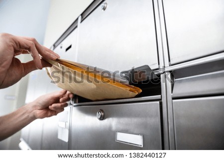 Close-up Of A Person's Hand Inserting Envelopes In Mailbox