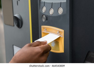 Close-up Of Person's Hand Inserting Ticket Into Parking Machine To Pay For Parking