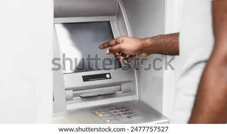 A close-up of a persons hand interacting with an ATM screen. The persons arm and shoulder are visible in the background.
