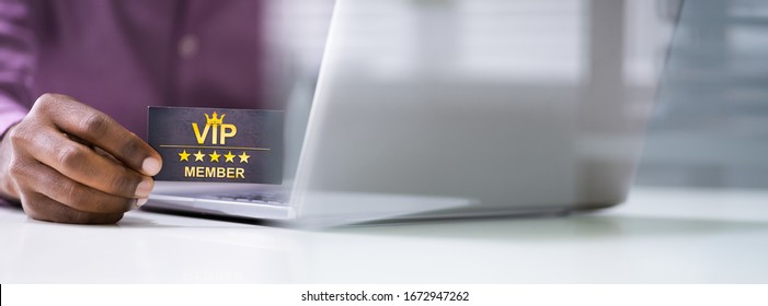 Close-up Of A Person's Hand With Loyalty Card Using Laptop