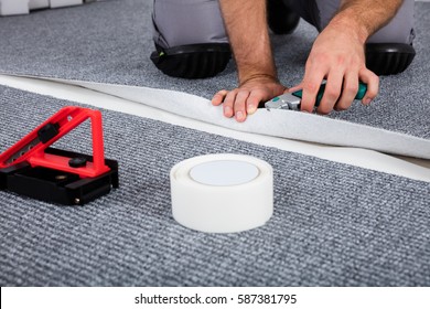 Close-up Of Person's Hand Lying Carpet Using Carpenter Tools