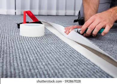 Close-up Of Person's Hand Lying Carpet Using Carpenter Tools