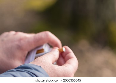 closeup person's hand pick a cigarette from the carton cigarettes pack box.Outdoor shot.