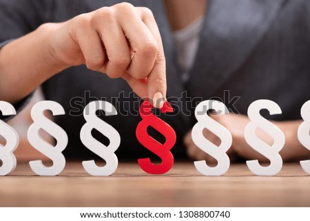 Close-up Of A Person's Hand Picking Red Paragraph Sign From Row On Wooden Surface
