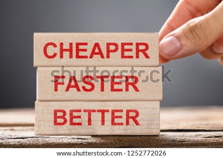 Close-up Of A Person's Hand Placing Cheaper, Faster And Better Wooden Blocks Over Desk