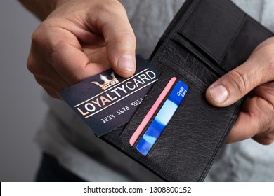 Close-up Of A Person's Hand Removing Black Loyalty Card From Wallet