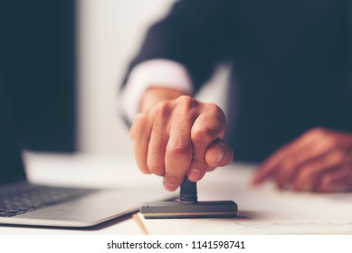Close-up Of A Person's Hand Stamping With Approved Stamp On Document At Desk, notary or business people work from home, isolated for coronavirus COVID-19 protection - Shutterstock ID 1141598741