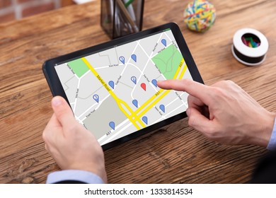 Close-up Of A Person's Hand Using GPS Map With Navigation Pointer On Digital Tablet