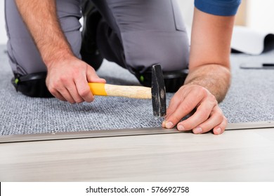 Close-up Of Person's Hand Using Hammer And Nail For Fixing Carpet