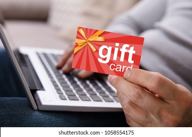 Close-up Of A Person's Hand Working On Laptop Holding Gift Card