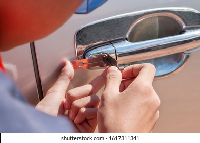 Close-up Of Person's Young Man Locksmith Hand Opening Bronze Car Door With Lock picker. Locksmith door opening device