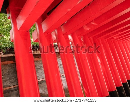 Close-up perspective of multiple bright red architectural pillars in a row, creating a rhythmic pattern. Inspired by traditional Japanese Torii gate design in an outdoor setting.