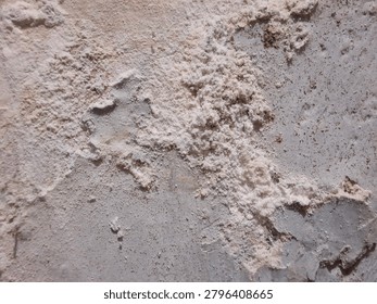 Close-up perspective of a wall surface undergoing deterioration, highlighting the jagged accumulation of powdery material against a fractured foundation. This composition captures the visceral reality of structural aging and the organic decay of construction elements.