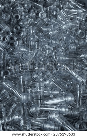 Close-up of PET preform blanks in a stack, used in plastic bottle manufacturing.