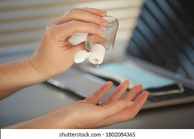 Closeup Pf Unrecognizable Woman Sanitizing Hands With Gel While Working At Desk In Post Pandemic Office, Copy Space