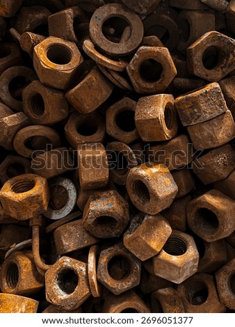 Close-Up phothograph of rusty metal nuts and bolts piled together, showing corroded texture, rough surfaces, and warm brown tone. 