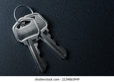 Closeup Photo Of 2 Metal Keys On A Circular Key Ring Over A Black Background.