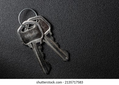 Closeup Photo Of 2 Metal Keys On A Circular Key Ring Over A Black Background.