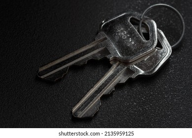 Closeup Photo Of 2 Metal Keys On A Circular Key Ring Over A Black Background.