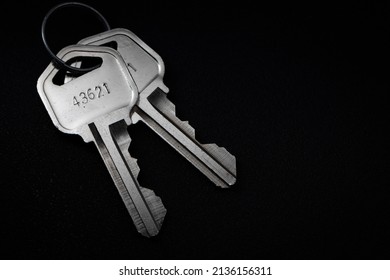 Closeup Photo Of 2 Metal Keys On A Circular Key Ring Over A Black Background.