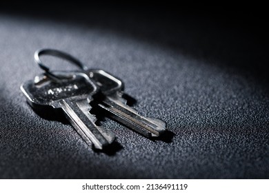 Closeup Photo Of 2 Metal Keys On A Circular Key Ring Over A Black Background.