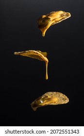 Closeup Photo Of 3 Nachos With Liquid Cheese Dripping And Jalapeno Slices On A Black Background.