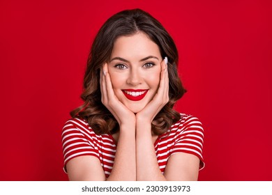 Closeup photo of adorable lady red lipstick pomade white shiny teeth hands on cheekbones good mood isolated red color background