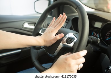 Closeup photo of annoyed woman driving car and honking