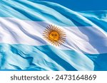 closeup photo of the Argentine flag, blue and white, with the yellow sun in the center, waving