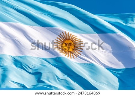 closeup photo of the Argentine flag, blue and white, with the yellow sun in the center, waving