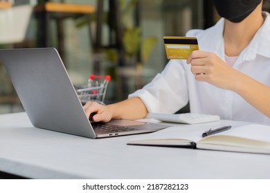 Close-up photo. Asian businesswoman holding credit card and using laptop computer smart phone to check her credit card balance. She analyzed the plan from the chart.