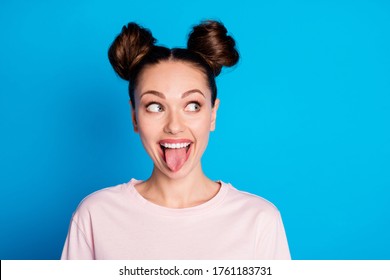 Closeup photo of attractive childish lady two funny buns stick tongue out mouth teasing boyfriend avoid look eyes bad behavior wear casual pink t-shirt isolated bright blue color background