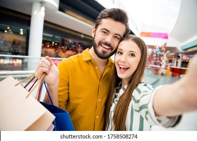 Closeup photo of attractive funny lady handsome guy couple visit shopping store mall together carry many bags packs taking making selfies good mood wear casual shirt outfit indoors