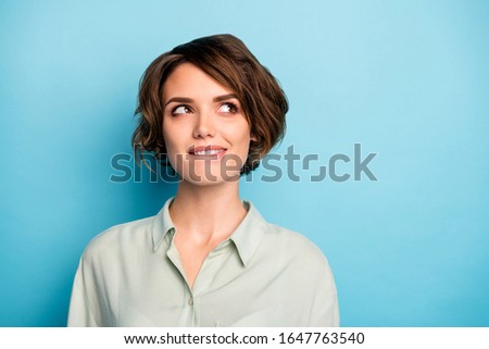 Closeup photo of attractive lady short hairdo wondered look up empty space biting lips have creative business idea wear casual green shirt isolated blue color background