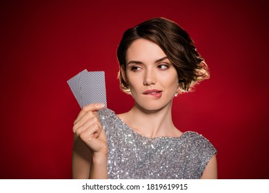 Closeup photo attractive tricky lady professional casino player hold two cards risky gamer all in cheating bluffing bite lips wear shine dress isolated dark red gradient color background