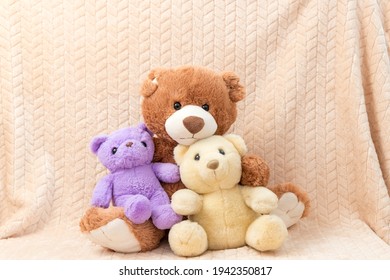 Close-up photo of bear family, soft stuffed children colorful toys on beige fabric. Valentines day, love and affection. Cute teddy bears on cloth. Concept of childhood and present