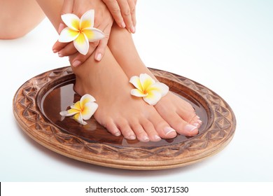 Closeup Photo Of A Beautiful Womens Legs With Perfect Pedicure Isolated On White Blue Background, Doing Spa Procedures With Water And Flowers, Beauty And Health Treatment Concept