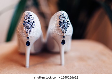 Closeup photo of a bride's shoes. Amazing white shoes with a bijouterie on them.