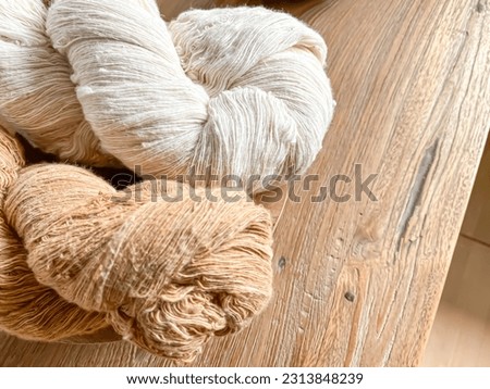 Close-up photo of brown and white cotton thread yarn on wooden table before winding. Plant hemp linen rope wool spool. Concept for traditional handmade textile, small industry, old fashioned, vintage.