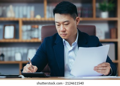 Close-up photo of businessman in office working on paper, serious and focused asian boss signing documents - Powered by Shutterstock