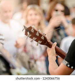 Closeup Photo Of Busker Plaing Guitar On City Street