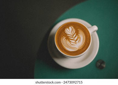 close-up photo of a cappuccino with latte art in a ceramic cup on a saucer. The cappuccino sits on a green wooden table with a white tablecloth. - Powered by Shutterstock