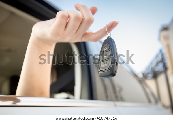Closeup photo\
of car keys hanging on female\
finger