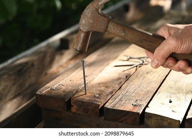 closeup photo of carpenter hammering nail into wood plank