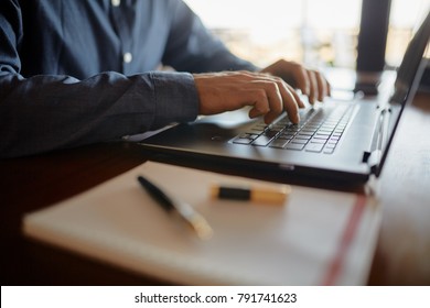 Close-up Photo Of Caucasian Male Hands Typing On Laptop Keyboard And Using Touchpad. Notebook And Pen On Foreground Of Workspace. Business Man Working On Computer. Isolated No Face View.