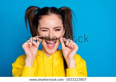 Closeup photo of charming pretty lady hold tail making fake mustache blinking eye like guy playful wear casual yellow hoodie pullover isolated bright blue color background