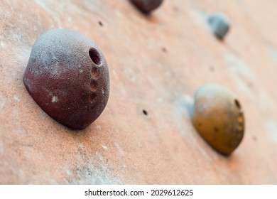 Close-up Photo Of Climbing Holds On Worn Wall Outside. Artificial Rock Climbing Wall At Park. Detail Of Bouldering Parkour. 