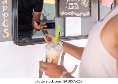 Close-up photo of a commercial interaction of a food truck offering contact less payment to a client - Powered by Shutterstock