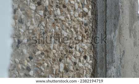 A close-up photo of a concrete wall with exposed aggregate. The photo shows the texture of the wall and the different colors of the aggregate