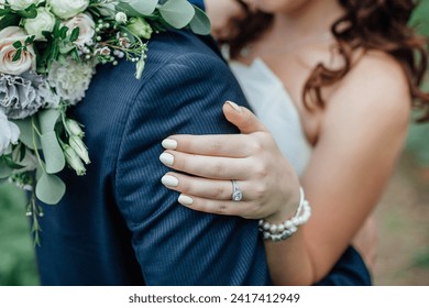 Close-up photo of a diamond engagement ring on the hands of a girl hugging a man in a jacket. - Powered by Shutterstock